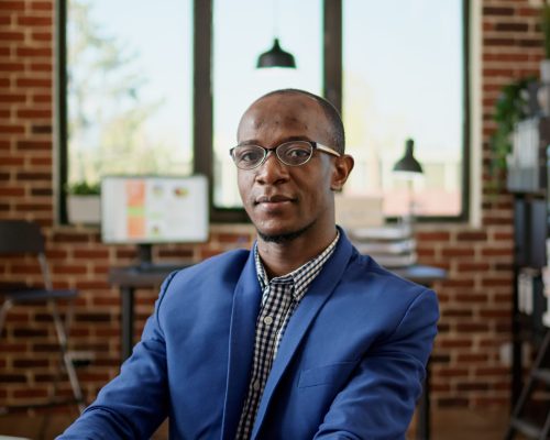 Portrait of businessman using laptop to browse internet in startup office, doing project research. Executive manager sending paperwork email, working on website browser application.