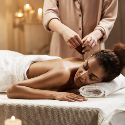 Tender beautiful african girl relaxing enjoying healthy spa massage with oil.