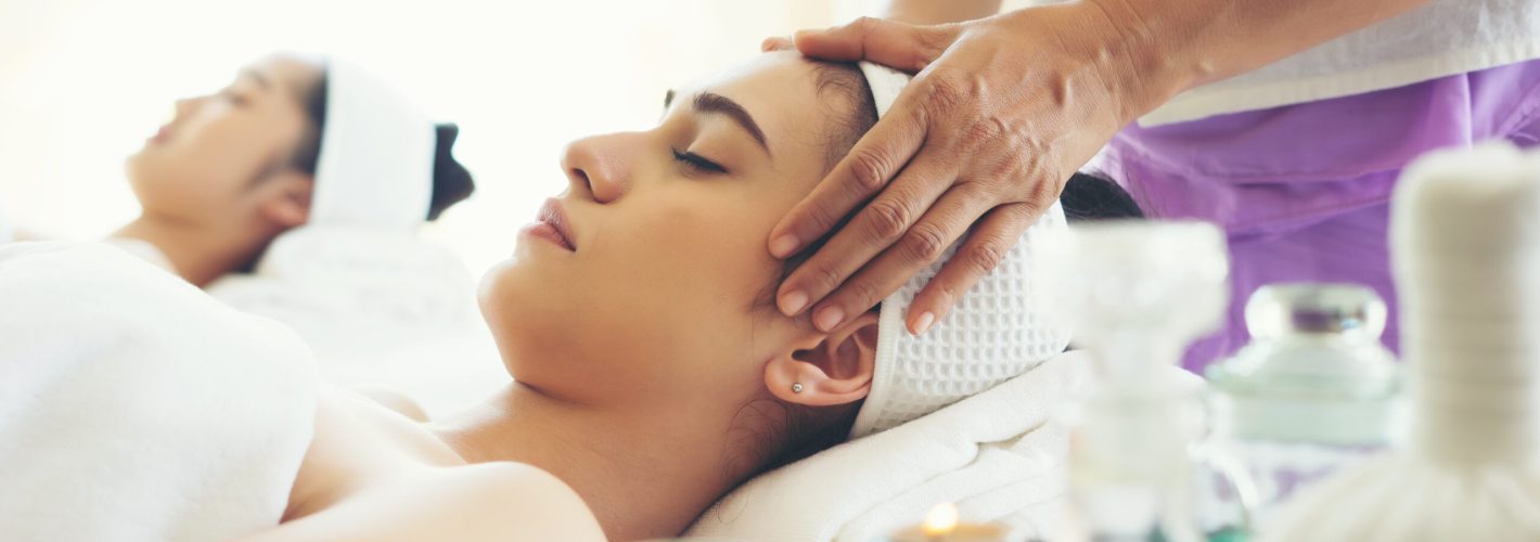 Young beautiful woman having face massage relaxing in spa.